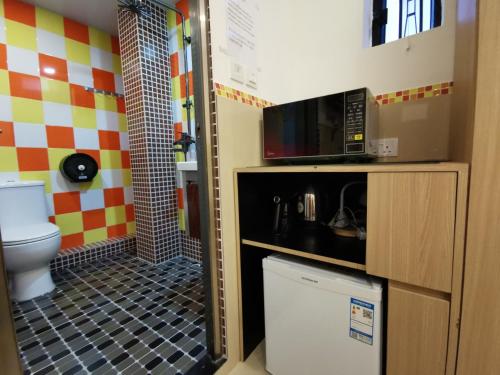 a bathroom with a toilet and a microwave at Hoi To Hostel in Hong Kong