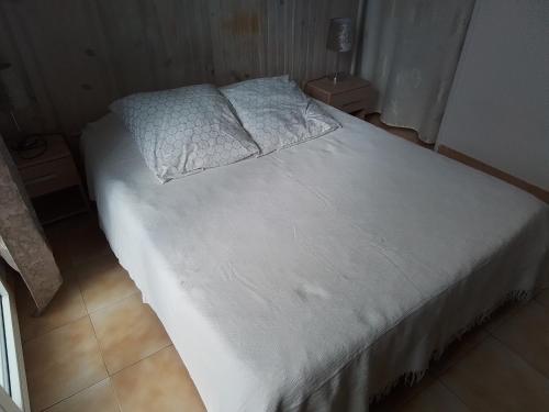 a bed with white sheets and pillows in a room at Les tournesols 28 in Lunel-Viel