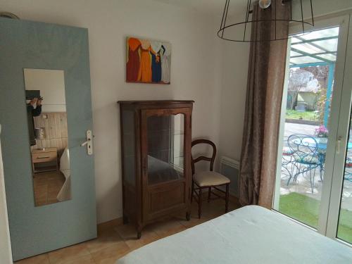 a bedroom with a mirror and a chair next to a door at Les tournesols 28 in Lunel-Viel