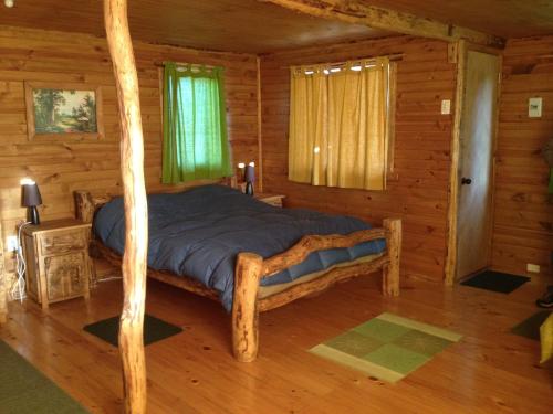 1 dormitorio con 1 cama en una cabaña de madera en La Casa Escondida, en Punta Arenas