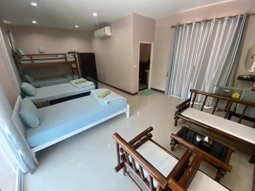 a small room with two beds and two chairs at บ้านชมเขา - Baan Chom Khao in Pak Chong