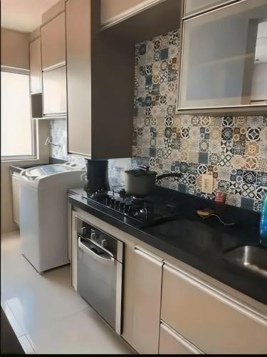 a kitchen with a stove top oven next to a sink at Apartamento bem localizado em fortaleza in Fortaleza