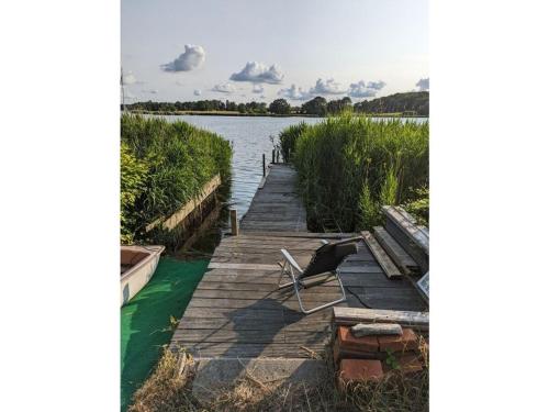 a chair sitting on a dock next to a lake at Schleipanorama Modern retreat in Brodersby