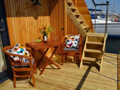 a wooden deck with a table and a staircase at Premium houseboat on the lake in Heiligenhafen