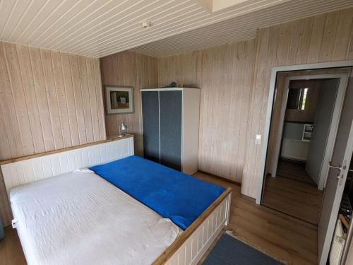 a small room with a bed with a blue blanket at Schleipanorama Modern retreat in Brodersby
