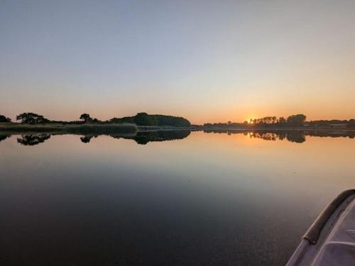 a boat on a lake with the sunset in the background at Schleipanorama Modern retreat in Brodersby