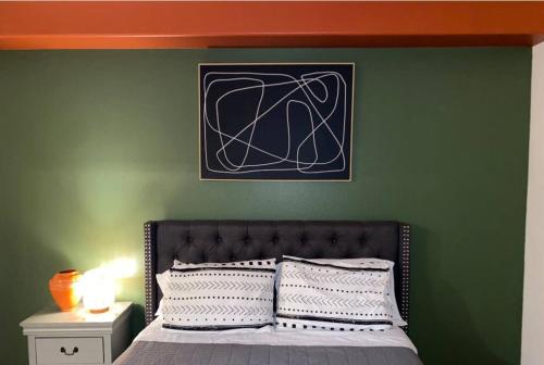 een slaapkamer met een groene muur en een bed bij Urban Haven at Orsini in Los Angeles