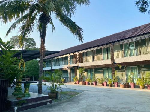 a building with palm trees in front of it at บ้านชมเขา - Baan Chom Khao in Pak Chong