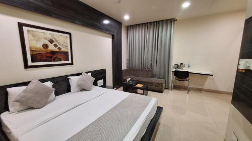 a bedroom with a large white bed and a desk at Hotel Alankar Palace in Bhopal