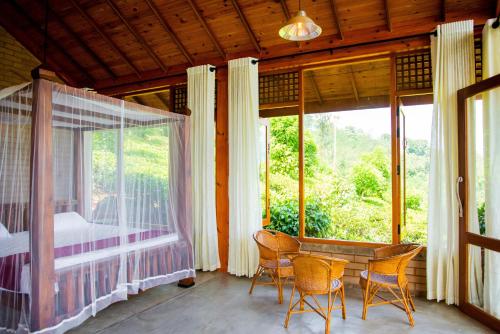 Zimmer mit einem Bett, einem Tisch und Stühlen in der Unterkunft Tea Forest Eco Lodge in Kandy