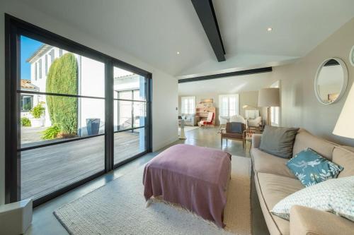 un salon avec un canapé et une grande fenêtre dans l'établissement Superbe maison d'architecte autour de sa piscine chauffée, à La Flotte