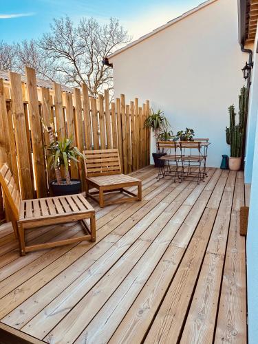 une terrasse en bois avec deux bancs et une table dans l'établissement Maison ensoleillée climatisée avec terrasse et parking, à Saint-Victor-la-Coste
