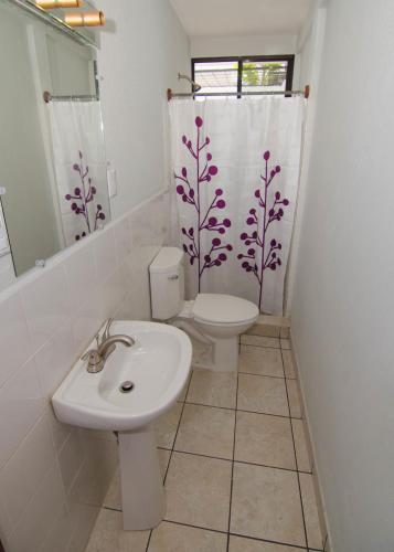 a bathroom with a toilet and a sink and a shower curtain at La Bicicleta Hostal in Managua