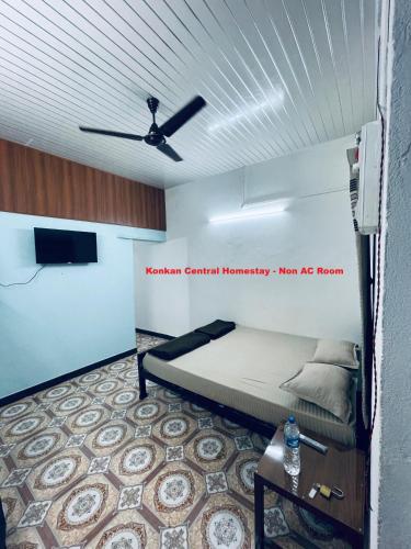 a bedroom with a bed and a ceiling fan at Konkan Central Kankavali - Home Stay in Kankauli