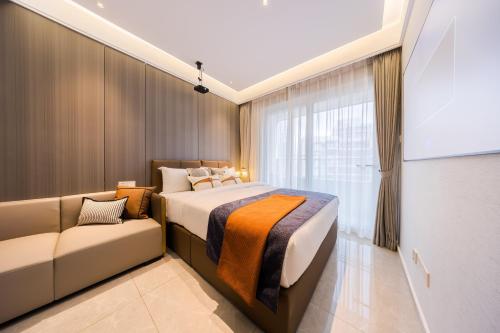 Xi Ke Executive Apartment - Shenzhen Futian Exhibition Center في شنجن: غرفة نوم بسرير واريكة