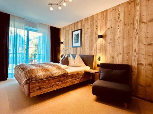 a bedroom with a bed and a chair at Sonn-Alm Chalet-Apartments in Bichlbach