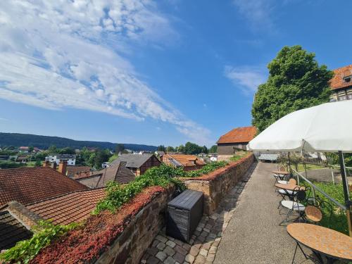 a patio with tables and chairs and a white umbrella at Hotel & Café Schachtenburg in Schlitz