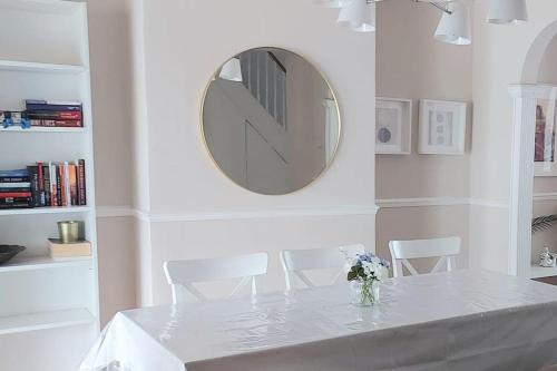 uma sala de jantar branca com uma mesa e um espelho em Beautiful Bright Three Bedroom House in Brighton and Hove with free parking em Portslade
