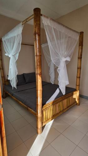 a wooden bed with curtains on it in a room at Mangoverde Guesthouse in Moalboal