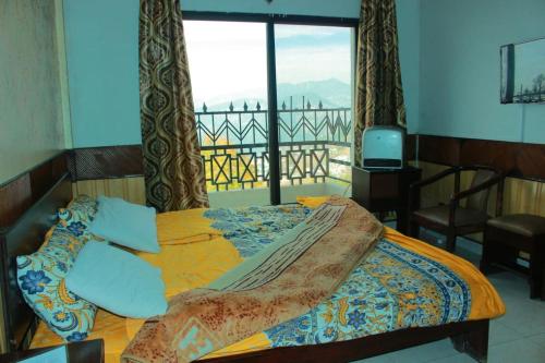 a bedroom with a bed with a view of a balcony at Mount Heaven Hotel Murree in Murree