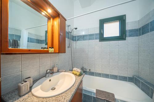 ein Badezimmer mit einem Waschbecken, einer Badewanne und einem Spiegel in der Unterkunft The Square Suites 2nd floor apartment in Argostoli