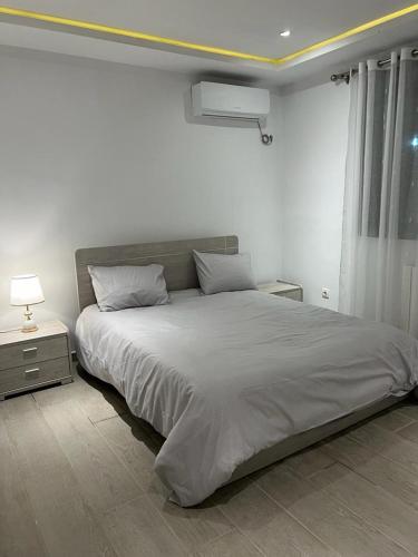 biała sypialnia z dużym łóżkiem i oknem w obiekcie Pavillon bouchaoui w mieście Cheraga
