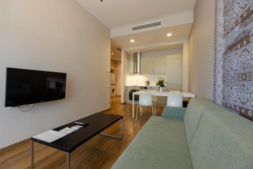 a living room with a couch and a tv on a wall at Le Port Boutique Apart Hotel in Batumi