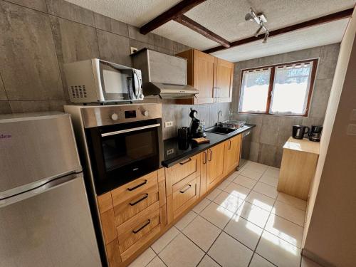 une cuisine avec un réfrigérateur et un micro-ondes dans l'établissement L'étape du plateau de Corréo, à La Roche-des-Arnauds