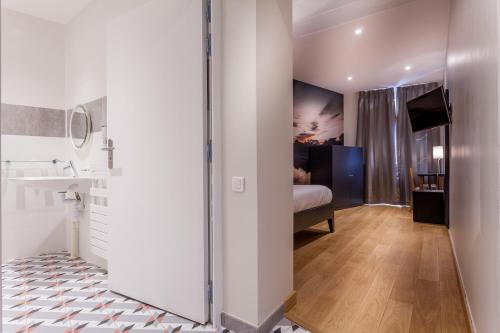 ein Bad mit einem Waschbecken und ein Bett in einem Zimmer in der Unterkunft Hotel Jenner in Paris
