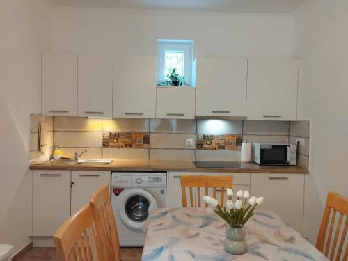 a kitchen with a table with a vase of flowers on it at Krisztina Vendégház in Zalaszentlászló