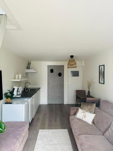 a living room with a couch and a kitchen at Hello Noordwijk - Zomerhuis Quarles van Uffordstraat in Noordwijk aan Zee