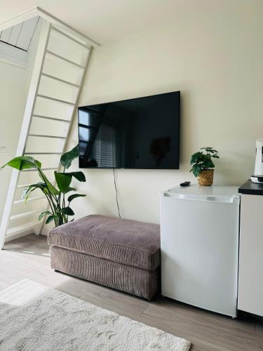 a living room with a ottoman and a tv on the wall at Hello Noordwijk - Zomerhuis Quarles van Uffordstraat in Noordwijk aan Zee
