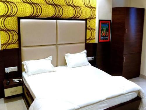 a bedroom with two white beds and a yellow wall at Lijoy Hotel & Restra in Būndi