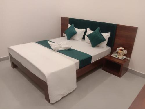ein Schlafzimmer mit einem großen Bett mit grünen und weißen Kissen in der Unterkunft Hotel Aagam Inn-Kota in Kota