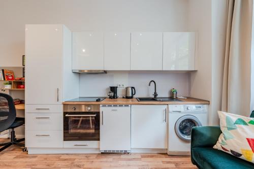 a kitchen with white cabinets and a washer and dryer at Spacious, central 3 room flat with gym & play area in Berlin