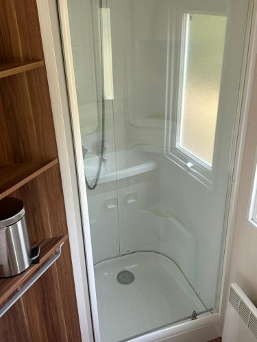 une douche avec une porte vitrée dans une salle de bain dans l'établissement Camping La sablière, à Saint-Jans-Cappel