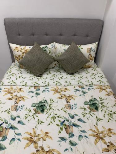 1 cama con colcha floral y 2 almohadas en Givande Studio at One PonteFino, en Batangas
