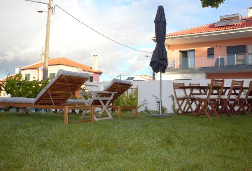 a group of chairs and an umbrella in the grass at Relax & Travel in Almada