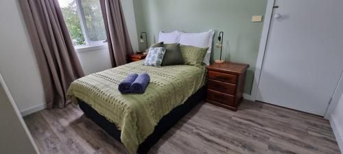 een slaapkamer met een bed met paarse handdoeken erop bij Views of the Tamar River in Clarence Point