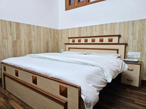 a bedroom with a large bed with white sheets at HOTEL CITY HEART in Chamba