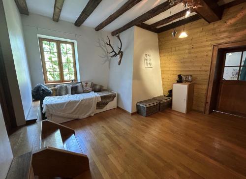 a living room with a bed and a wooden floor at Chambre familiale in Saint-Nabord
