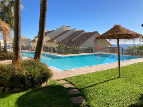 ein Pool mit Sonnenschirm und ein Gebäude in der Unterkunft Los Monteros Hill Club Marbella in Marbella
