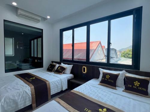 two beds in a room with a large window at The MC hotel mộc châu in Mộc Châu