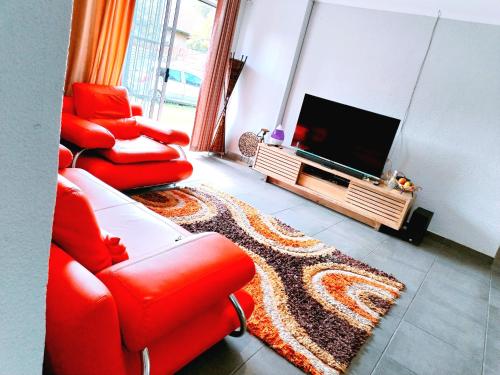 a living room with two red chairs and a flat screen tv at Reutlwane Gardens house in Secunda