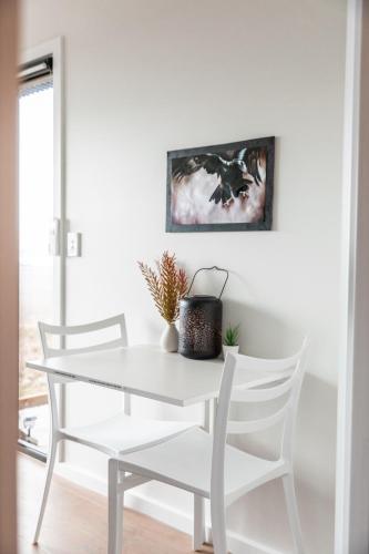 ein weißes Esszimmer mit einem weißen Tisch und Stühlen in der Unterkunft Eagle Peak Tiny Abode - Mystic Ridge Estate in Bywong