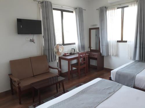 ein Hotelzimmer mit einem Bett, einem Stuhl und einem Schreibtisch in der Unterkunft Dragon Hotel in Pokhara