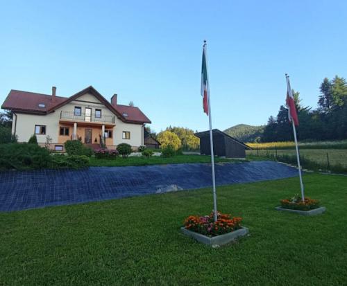 a house with two flags and flowers in a yard at Bystre 35 in Bystre