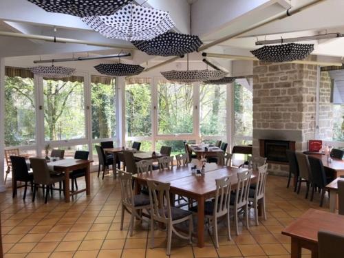 un restaurant avec des tables et des chaises en bois et des fenêtres dans l'établissement Domaine des Etangs de Taysse, à Espagnac