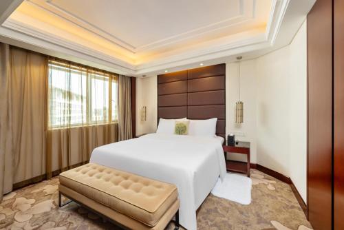 GuangDong Hotel Shanghai في شانغهاي: غرفة نوم بسرير ابيض كبير ومقعد