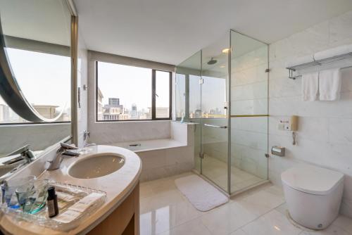uma casa de banho com um lavatório e uma cabina de duche em vidro. em GuangDong Hotel Shanghai em Xangai